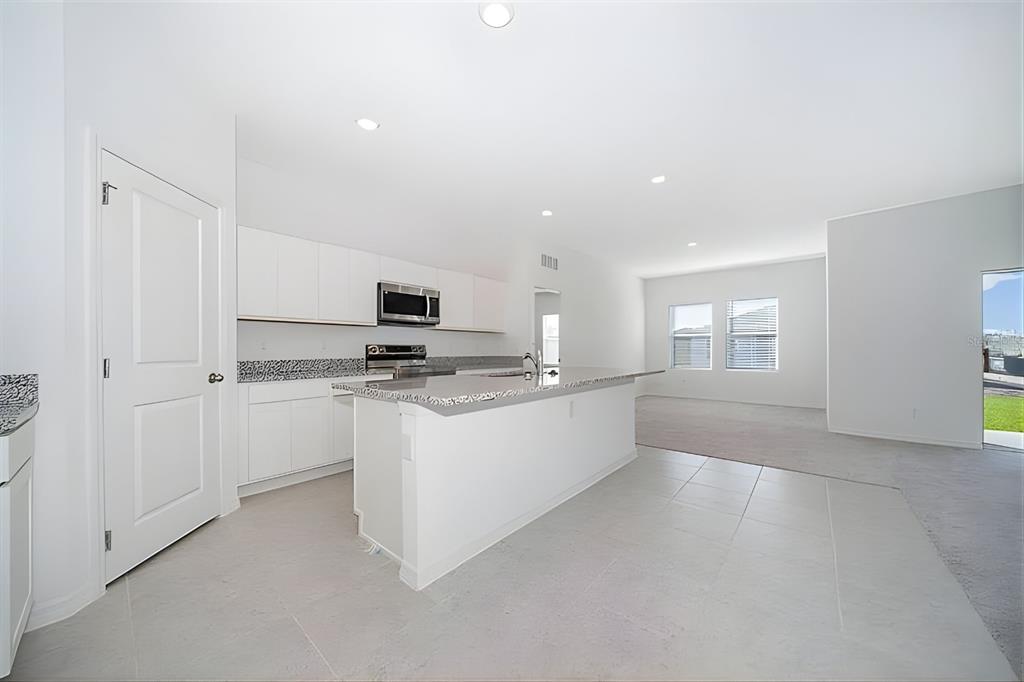5844 Bovine Drive St. Cloud, FL 34771 - Photo 6 of 21 a kitchen with granite countertop white cabinets and white appliances