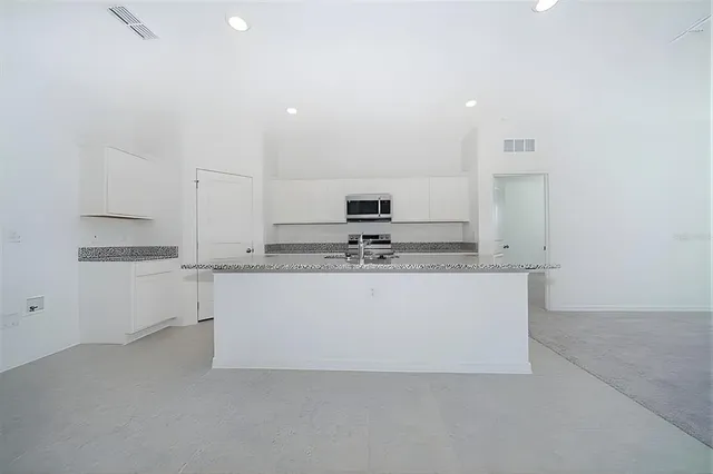 a large white kitchen with kitchen island a sink a stove and white cabinets