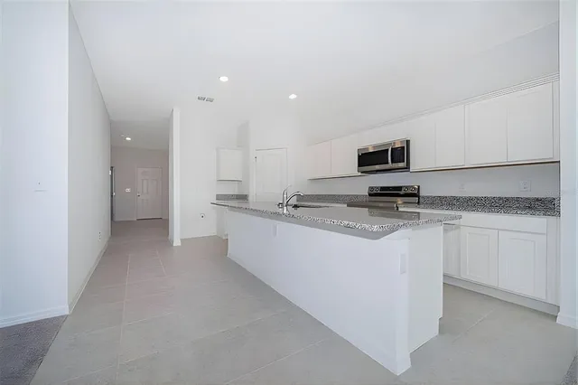 a kitchen with kitchen island granite countertop a sink stove and refrigerator
