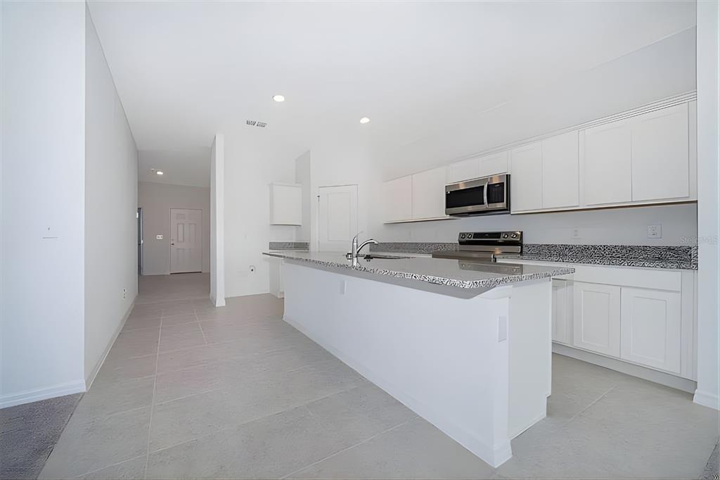 5844 Bovine Drive St. Cloud, FL 34771 - Photo 8 of 21 a kitchen with kitchen island granite countertop a sink stove and refrigerator