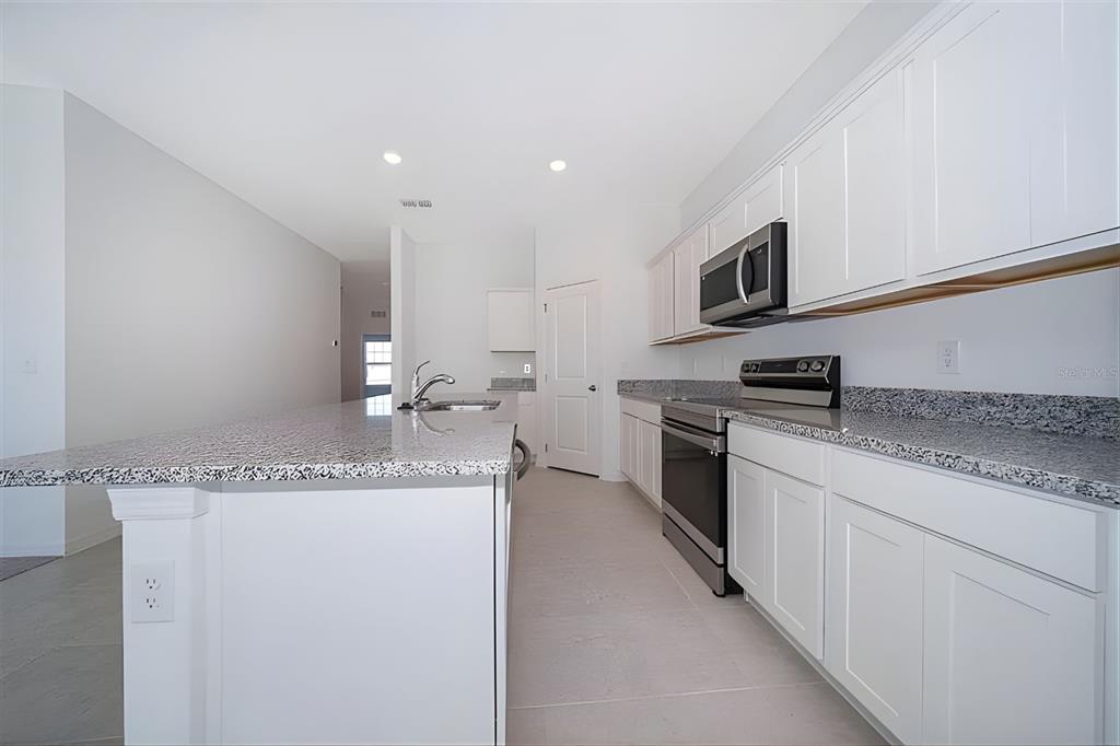 5844 Bovine Drive St. Cloud, FL 34771 - Photo 10 of 21 a kitchen with stainless steel appliances granite countertop a sink and a stove