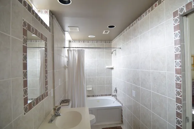 a bathroom with a bathtub shower sink vanity and toilet