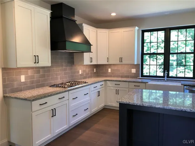 a kitchen with granite countertop white cabinets stainless steel appliances a sink and a window