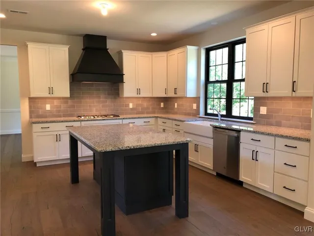 a kitchen with granite countertop kitchen island a sink cabinets and window
