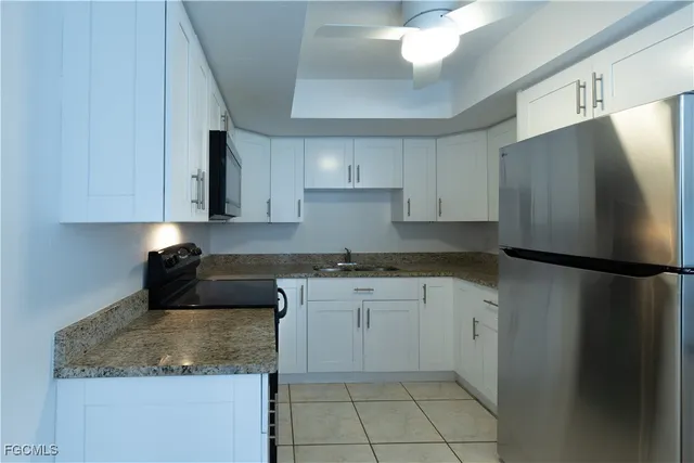 a kitchen with granite countertop a sink dishwasher a stove and a microwave oven on cabinets