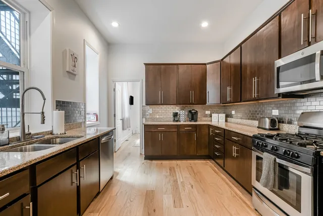 a kitchen with stainless steel appliances granite countertop wooden cabinets a stove top oven a sink and dishwasher