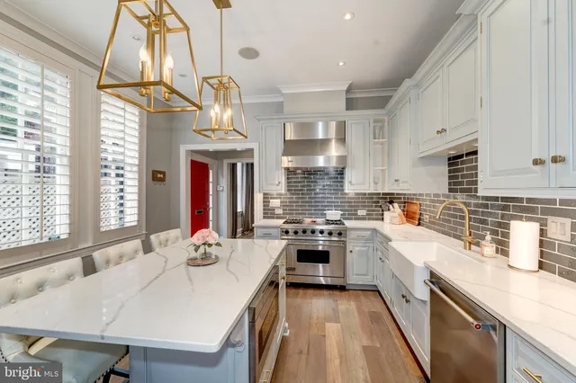 a kitchen with stainless steel appliances a stove a sink dishwasher a stove and a dining table with wooden floor