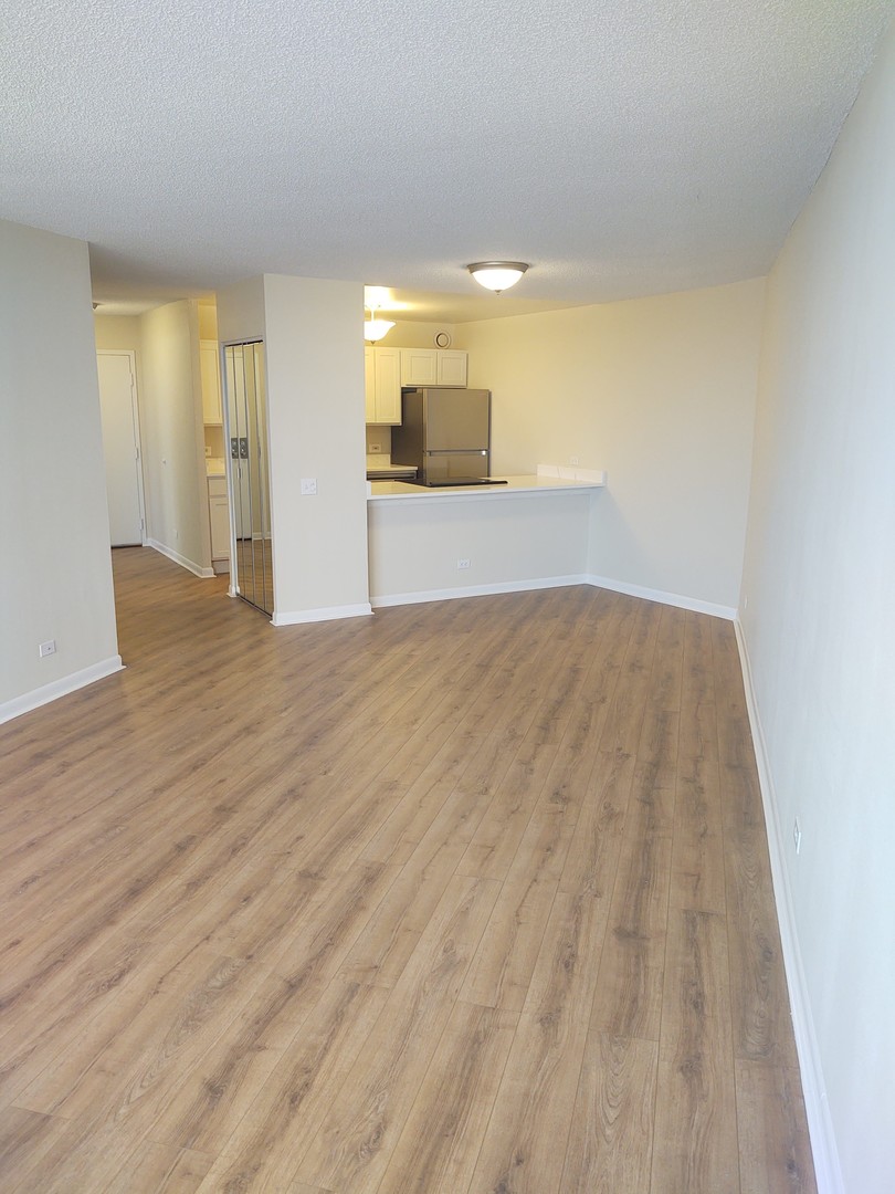 5320 North Sheridan Road, Unit 407 Chicago, IL 60640 - Photo 11 of 26 a view of empty room with wooden floor and fireplace