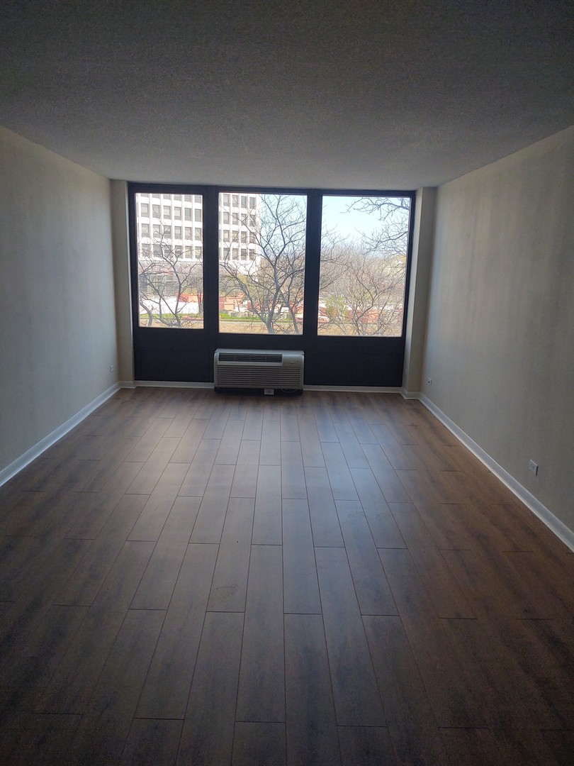5320 North Sheridan Road, Unit 407 Chicago, IL 60640 - Photo 12 of 26 an empty room with wooden floor and windows