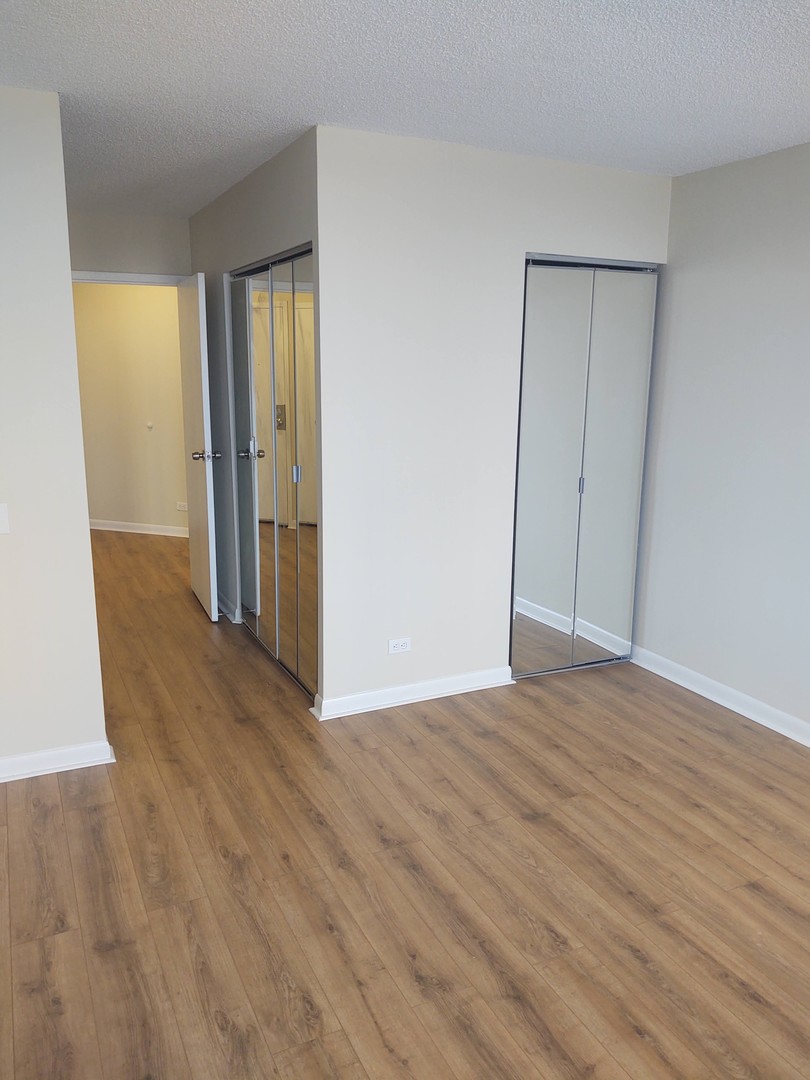 5320 North Sheridan Road, Unit 407 Chicago, IL 60640 - Photo 16 of 26 a view of an empty room with wooden floor and a window