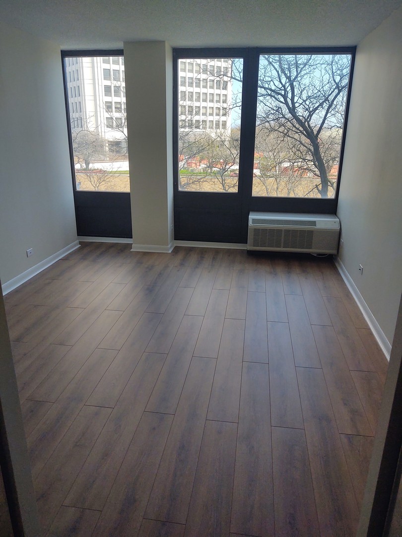 5320 North Sheridan Road, Unit 407 Chicago, IL 60640 - Photo 17 of 26 an empty room with wooden floor and windows