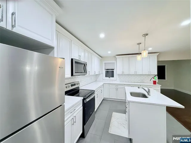 a kitchen with white cabinets and stainless steel appliances