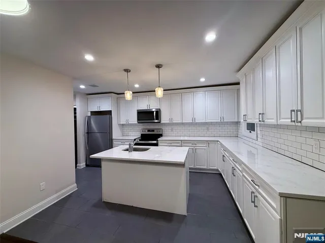 a kitchen with stainless steel appliances kitchen island granite countertop a sink a stove and refrigerator