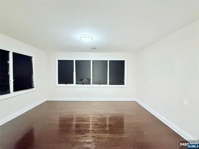 a view of an empty room with wooden floor and windows