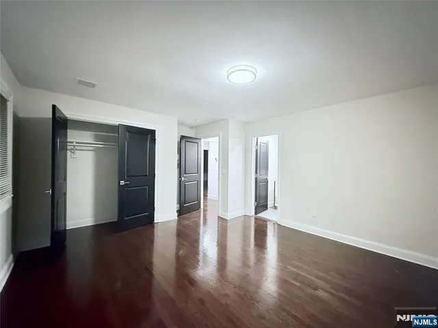 a view of an empty room with wooden floor and closet