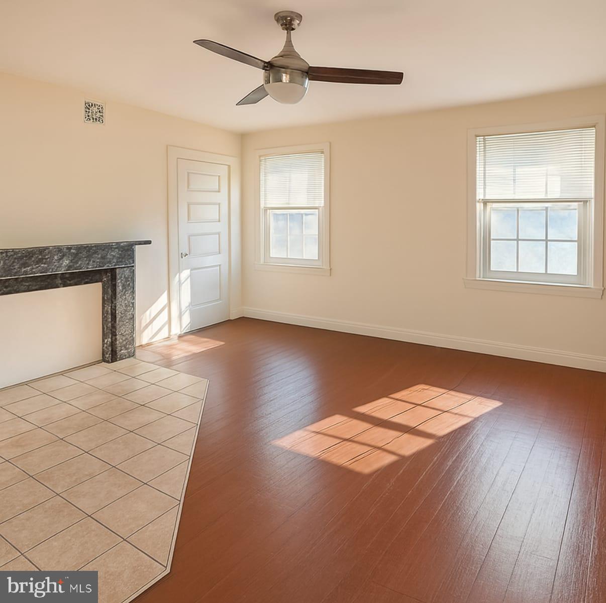 a view of an empty room with a window and wooden floor