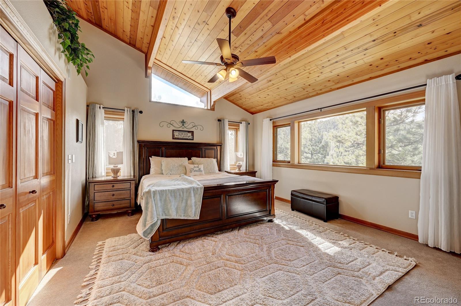 27164 Sun Ridge Drive Evergreen, CO 80439 - Photo 19 of 40 a spacious bedroom with a large bed and a window