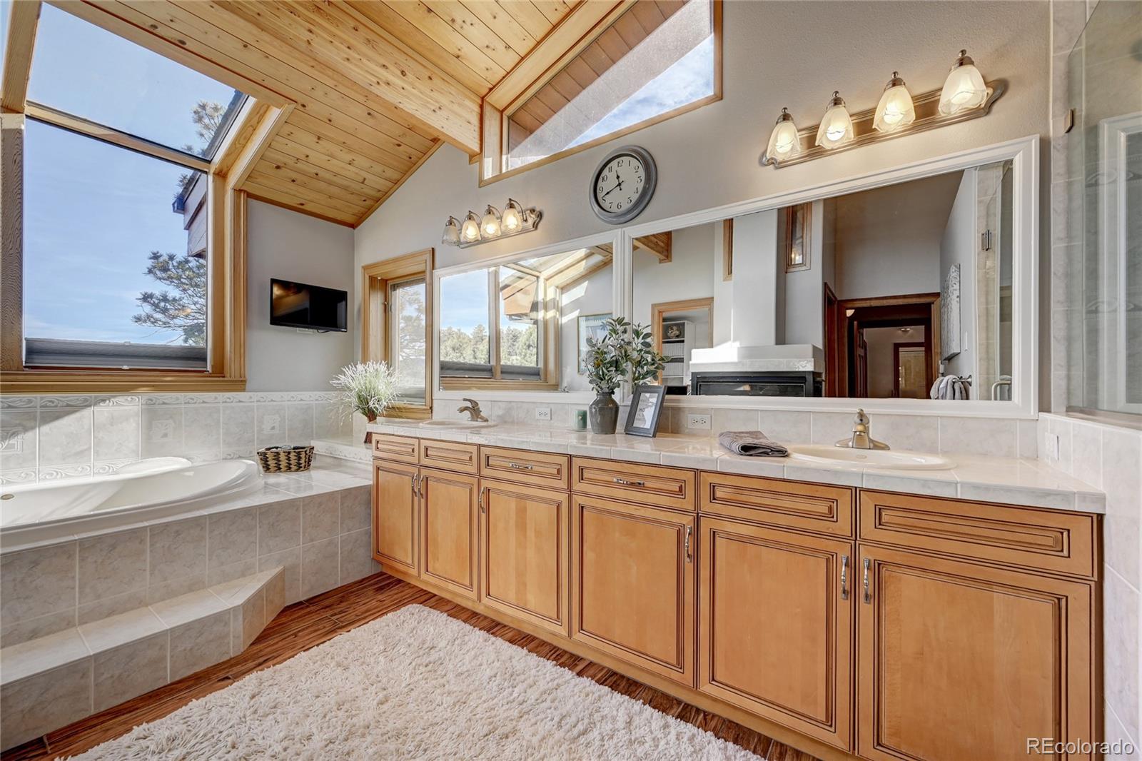 27164 Sun Ridge Drive Evergreen, CO 80439 - Photo 21 of 40 a spacious bathroom with a double vanity sink and a large mirror