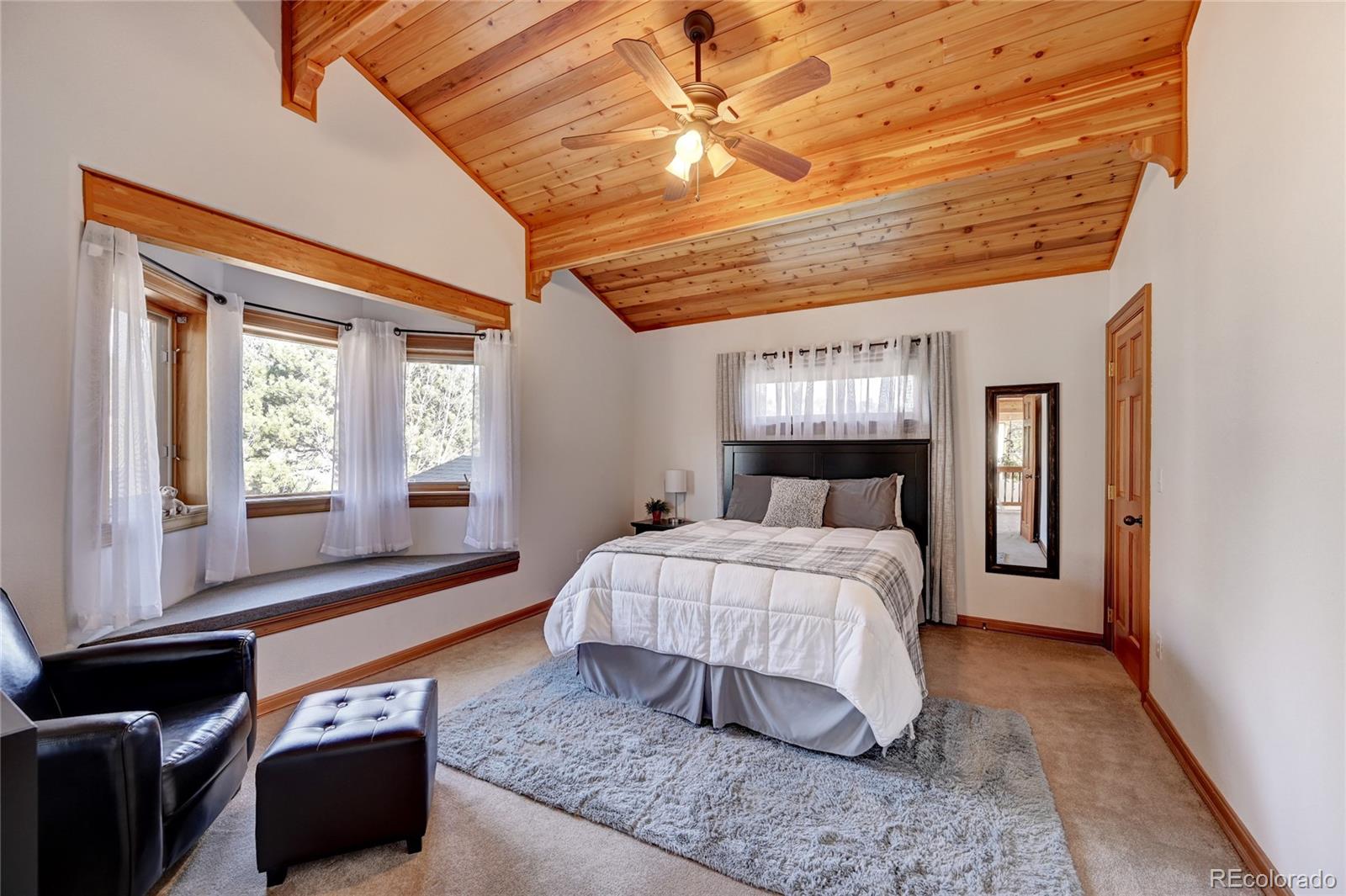 27164 Sun Ridge Drive Evergreen, CO 80439 - Photo 26 of 40 a bedroom with a bed and a chandelier