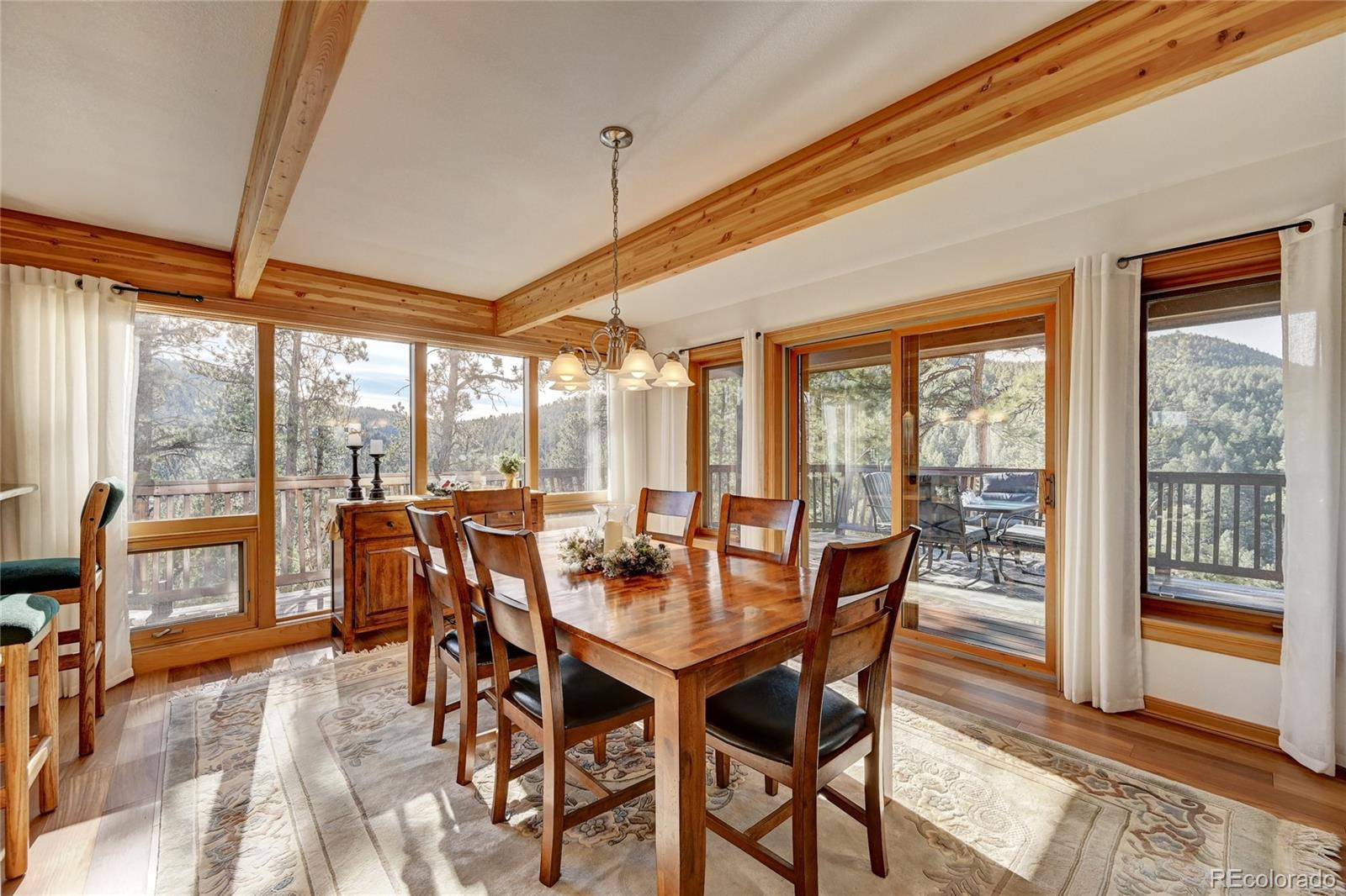 27164 Sun Ridge Drive Evergreen, CO 80439 - Photo 10 of 40 a view of a dining room with furniture large windows and wooden floor