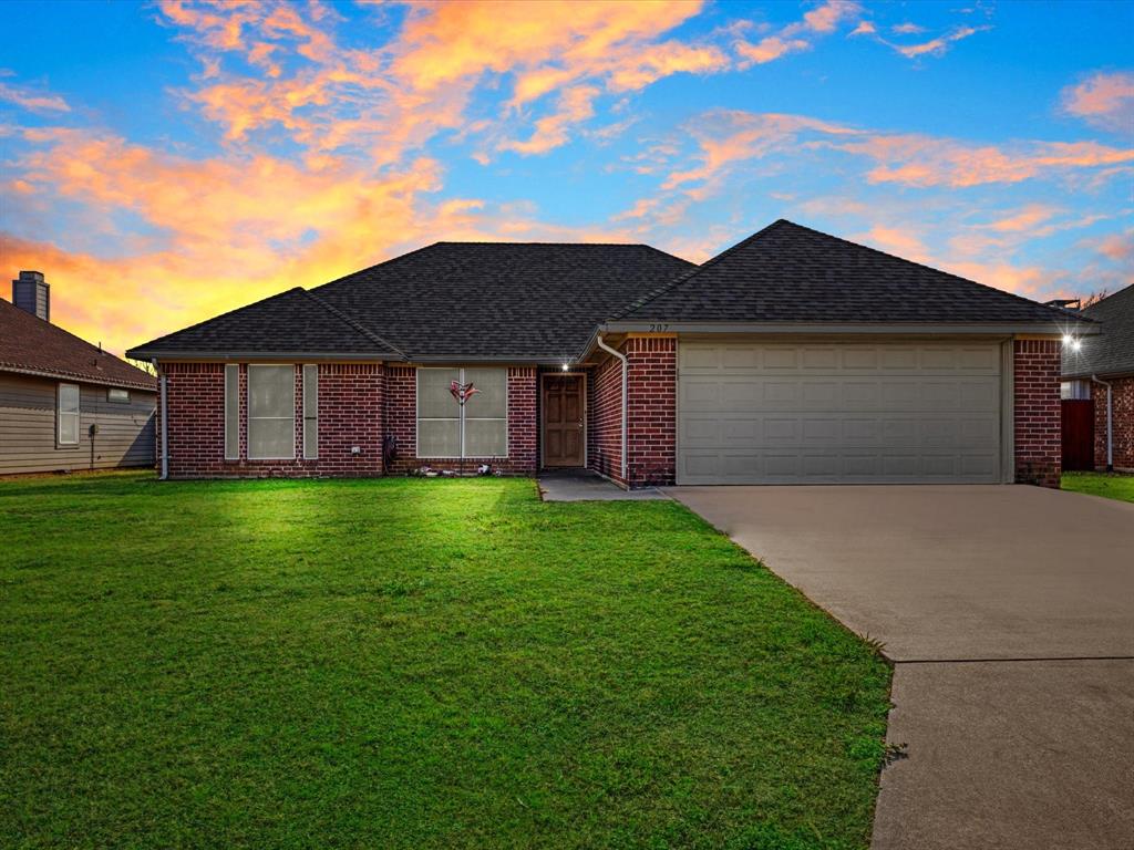 207 Quail Run Aubrey, TX 76227 - Photo 3 of 30 View of front of home featuring a lawn, brick siding, roof with shingles, driveway, and an attached garage