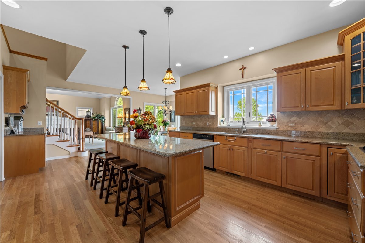 430 Alberosky Way Batavia, IL 60510 - Photo 17 of 49 a kitchen with stainless steel appliances granite countertop a kitchen island a stove a sink a dining table and chairs with wooden floor