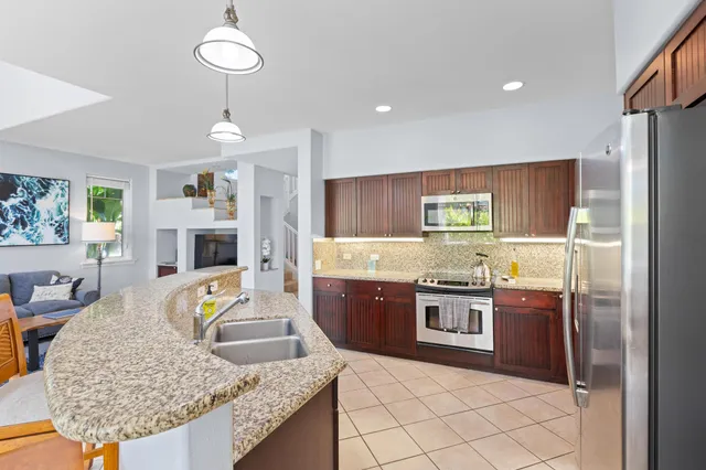 a kitchen with kitchen island granite countertop wooden cabinets a refrigerator and a stove
