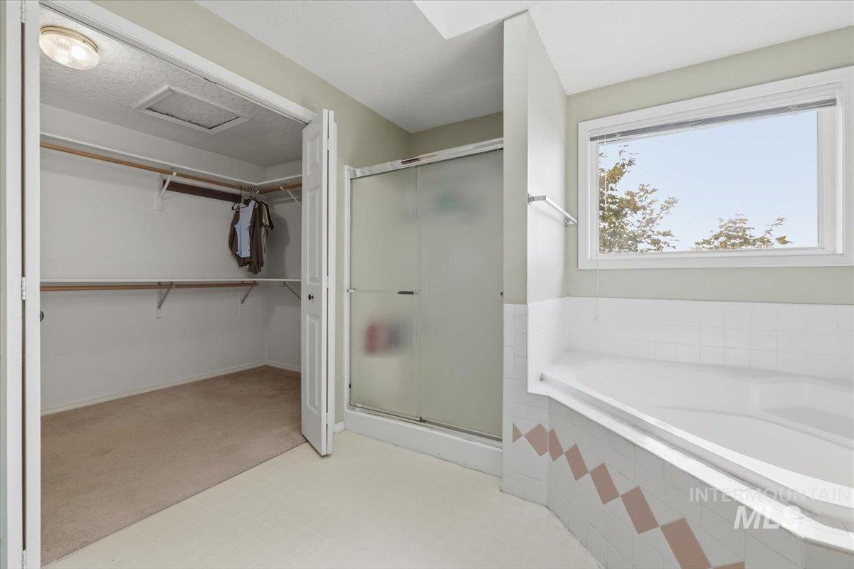24440 Kenridge Road Caldwell, ID 83607 - Photo 34 of 48 Spacious bathroom featuring a built-in soaking tub, a separate shower with a frosted glass enclosure, and a walk-in closet with built-in shelving