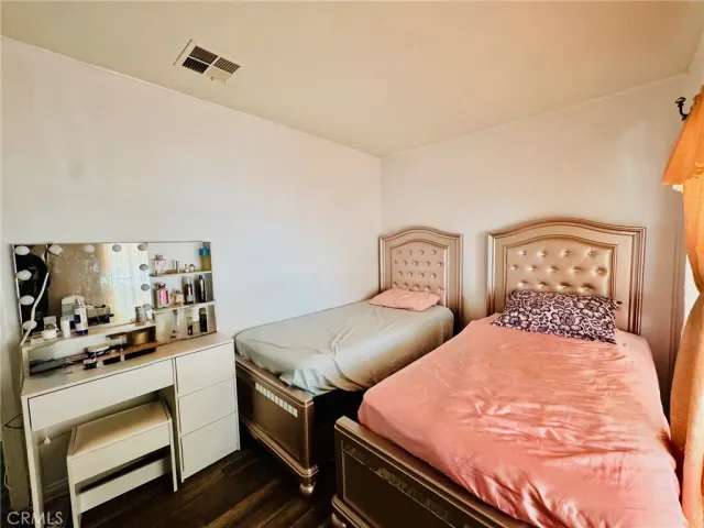 a bedroom with a bed a dresser with wooden floor