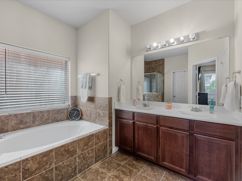 21554 Rainfall Park Drive Spring, TX 77388 - Photo 18 of 36 Primary bathroom features a spacious layout with a large soaking tub, dual sinks with a wide mirror.
