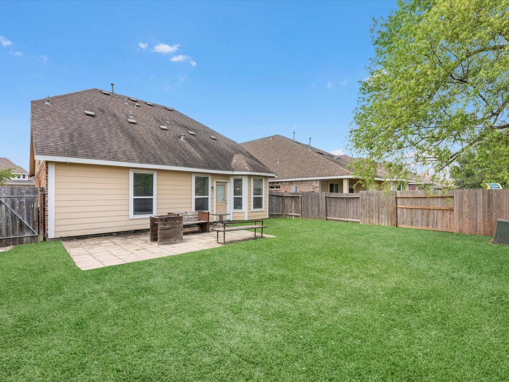 21554 Rainfall Park Drive Spring, TX 77388 - Photo 32 of 36 Spacious backyard with a well-maintained lawn, a patio area, and a wooden fence for privacy.