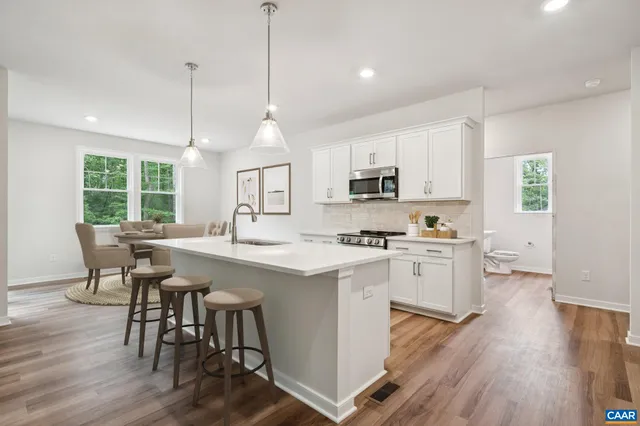 a kitchen with kitchen island granite countertop a sink a counter space appliances and cabinets