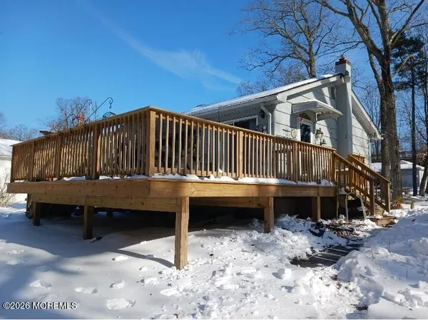 a view of a house with a wooden deck and a forest