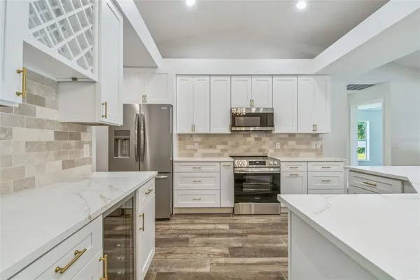 a hallway with a stove a faucet white cabinets and a potted plant