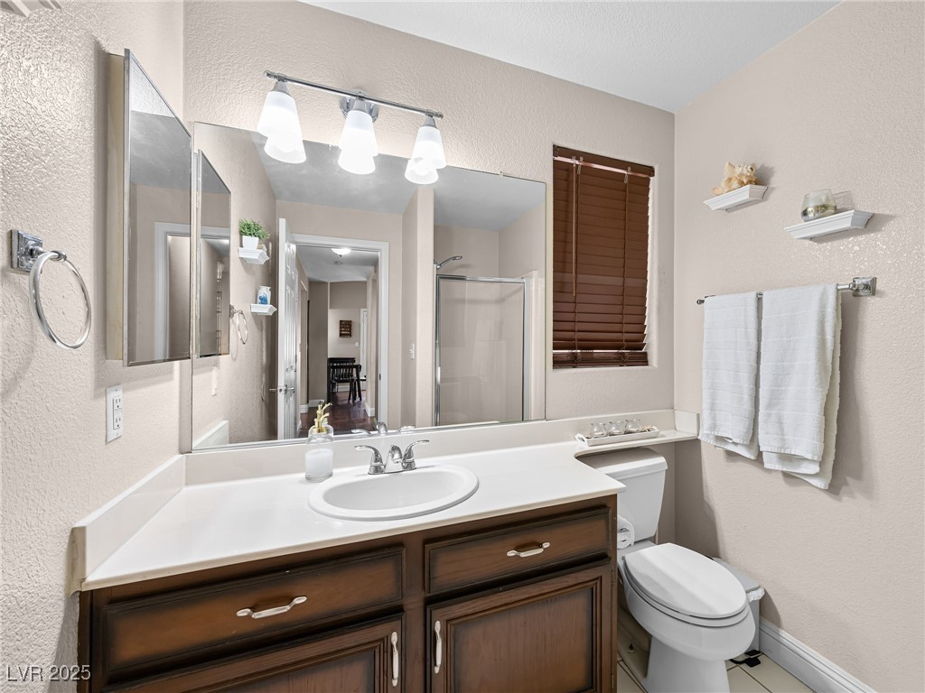 353 Seine Way, Unit N Henderson, NV 89014 - Photo 17 of 36 Full bath with vanity, a shower stall, toilet, and a textured wall.
