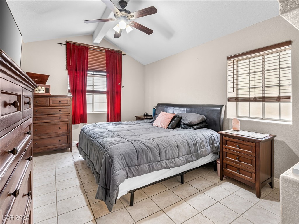 353 Seine Way, Unit N Henderson, NV 89014 - Photo 23 of 36 Bedroom featuring vaulted ceiling with beams, light tile patterned flooring, and ceiling fan.