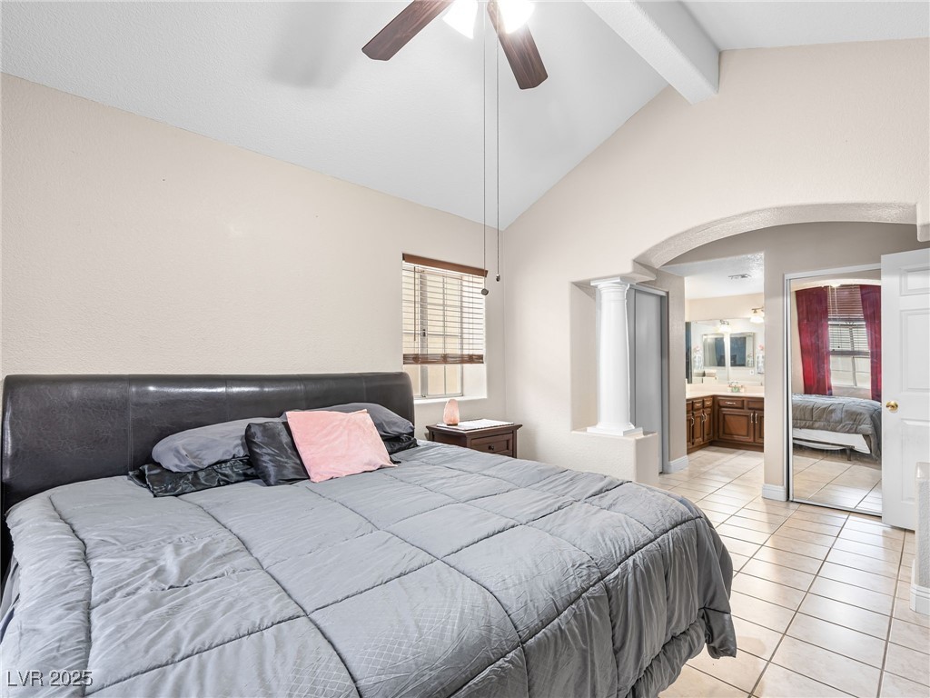 353 Seine Way, Unit N Henderson, NV 89014 - Photo 25 of 36 Bedroom with light tile patterned floors, lofted ceiling with beams, arched walkways, ceiling fan, and ensuite bathroom.