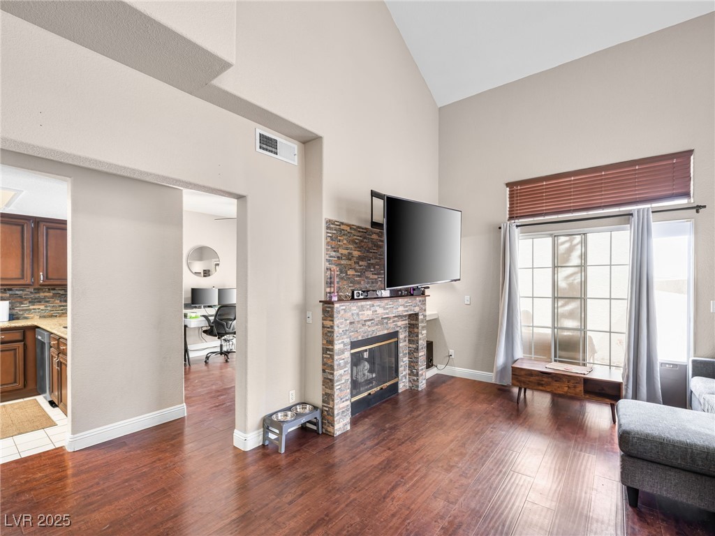 353 Seine Way, Unit N Henderson, NV 89014 - Photo 7 of 36 Living area featuring visible vents, a fireplace, high vaulted ceiling, and wood finished floors.