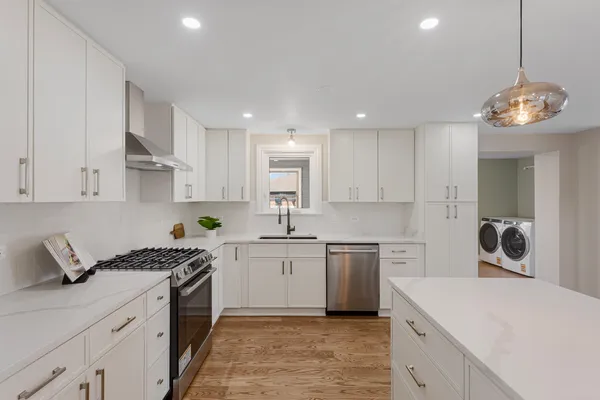 a kitchen that has a lot of cabinets in it and wooden floors