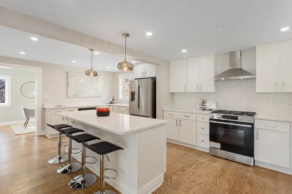 a kitchen with a stove a refrigerator and a dining table with wooden floor