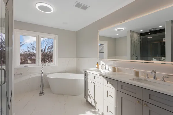 a bathroom with a double vanity sink a mirror and a bathtub