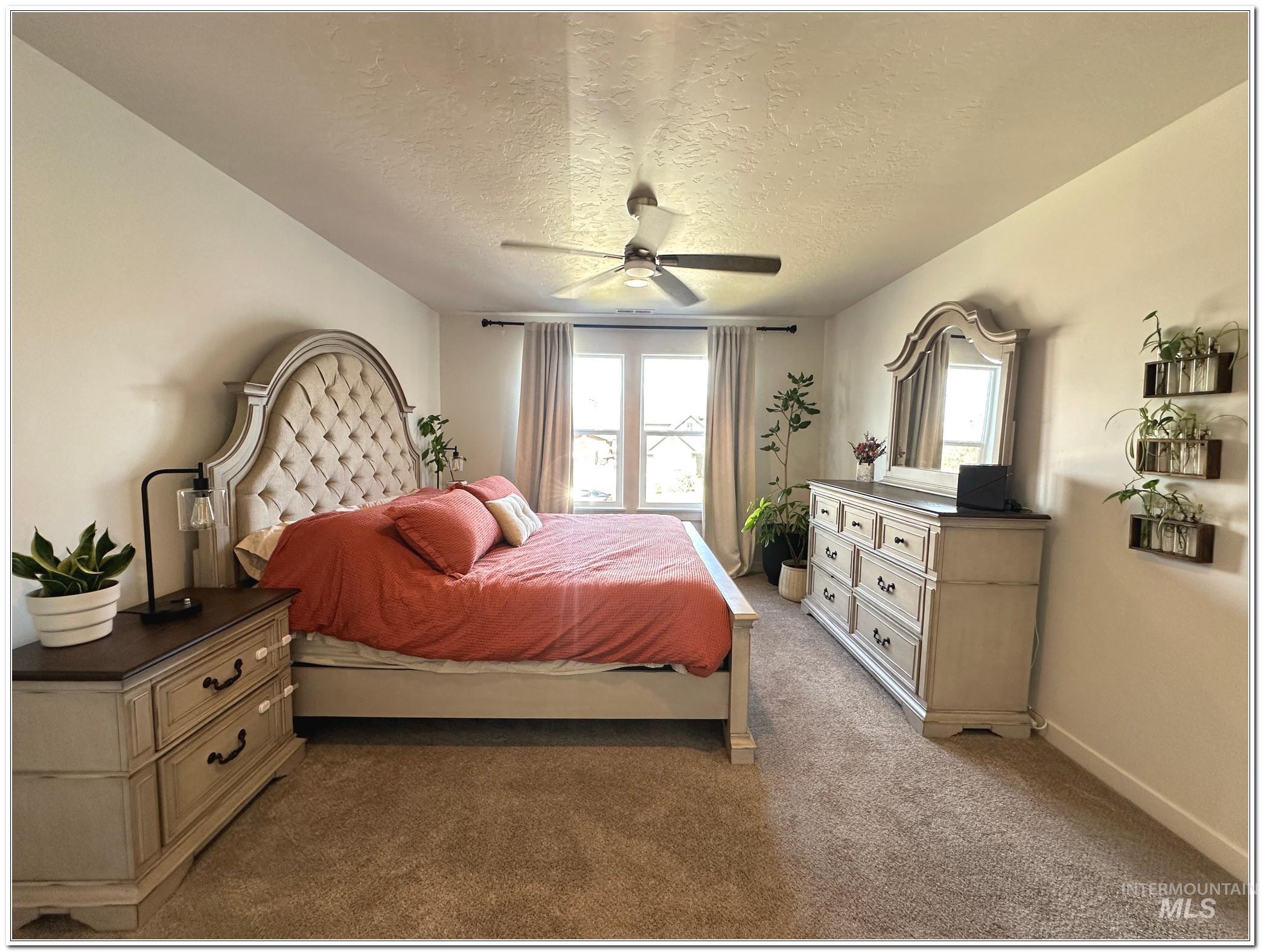 9687 West Arnold Road Boise, ID 83714 - Photo 19 of 49 Carpeted bedroom with a textured ceiling, multiple windows, and a ceiling fan