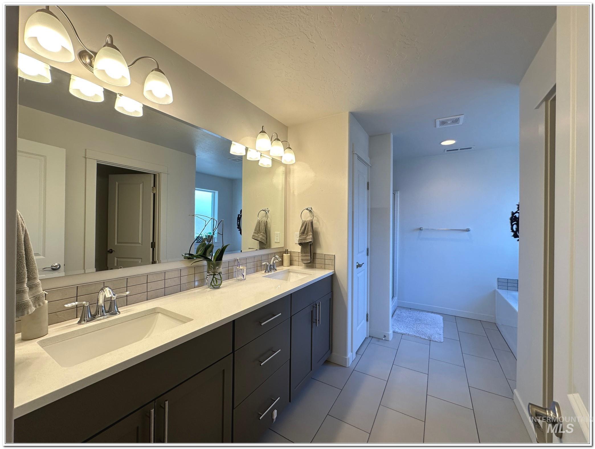 9687 West Arnold Road Boise, ID 83714 - Photo 21 of 49 Full bath featuring double vanity, a bath, and light tile patterned flooring