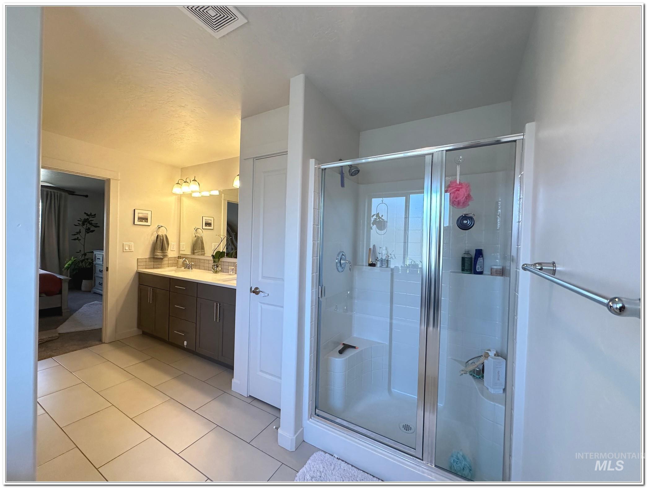 9687 West Arnold Road Boise, ID 83714 - Photo 23 of 49 Bathroom featuring double vanity, connected bathroom, a shower stall, and light tile patterned floors