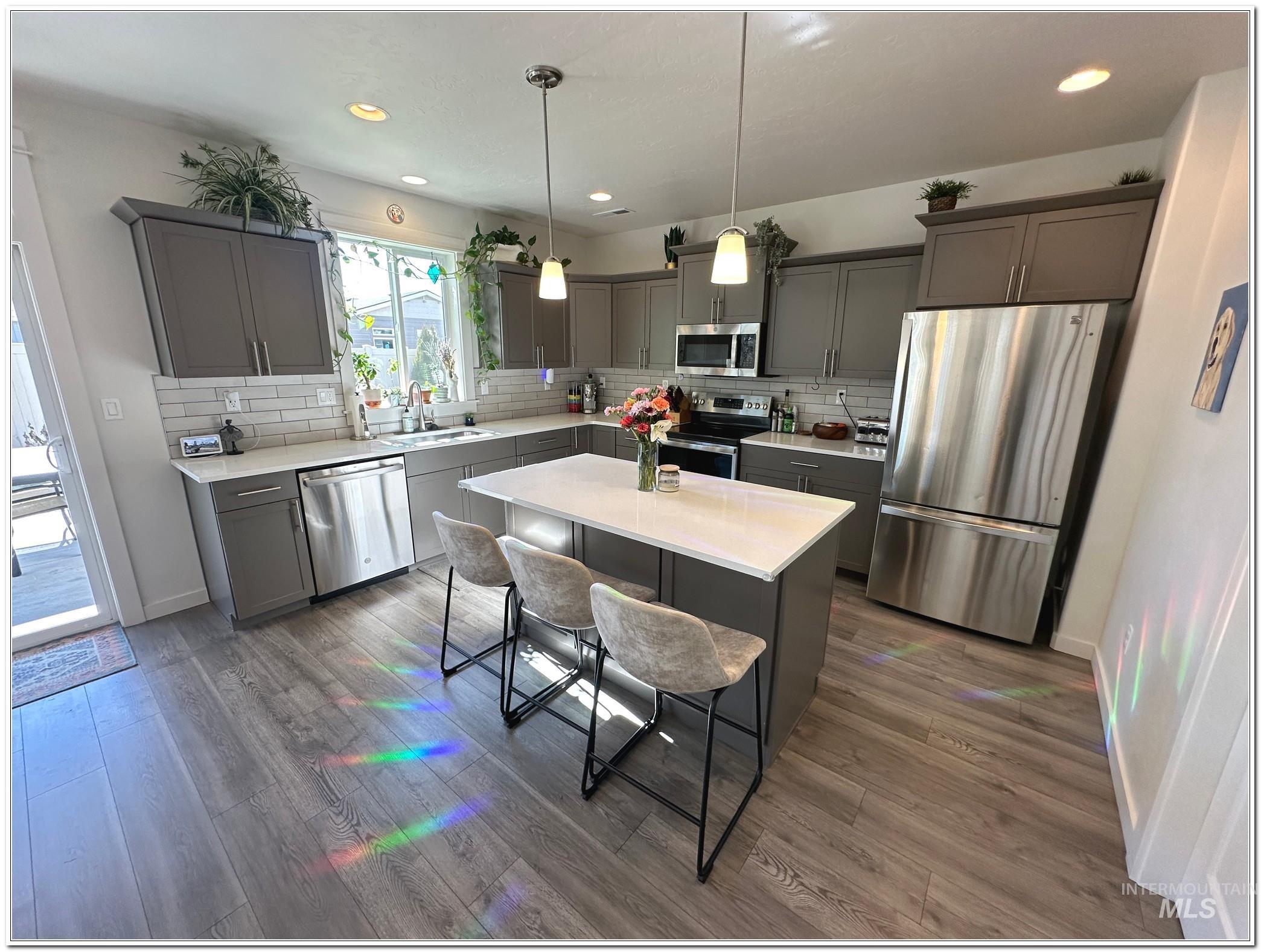 9687 West Arnold Road Boise, ID 83714 - Photo 3 of 49 Kitchen featuring stainless steel appliances, decorative light fixtures, a center island, a kitchen breakfast bar, and dark wood finished floors