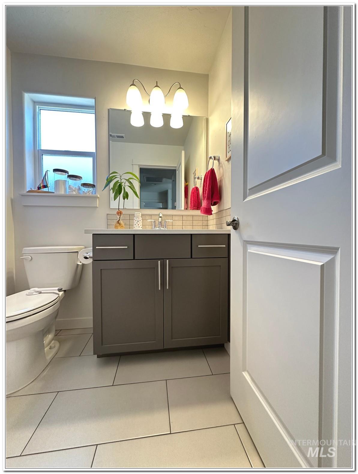 9687 West Arnold Road Boise, ID 83714 - Photo 32 of 49 Bathroom with vanity, light tile patterned flooring, and decorative backsplash