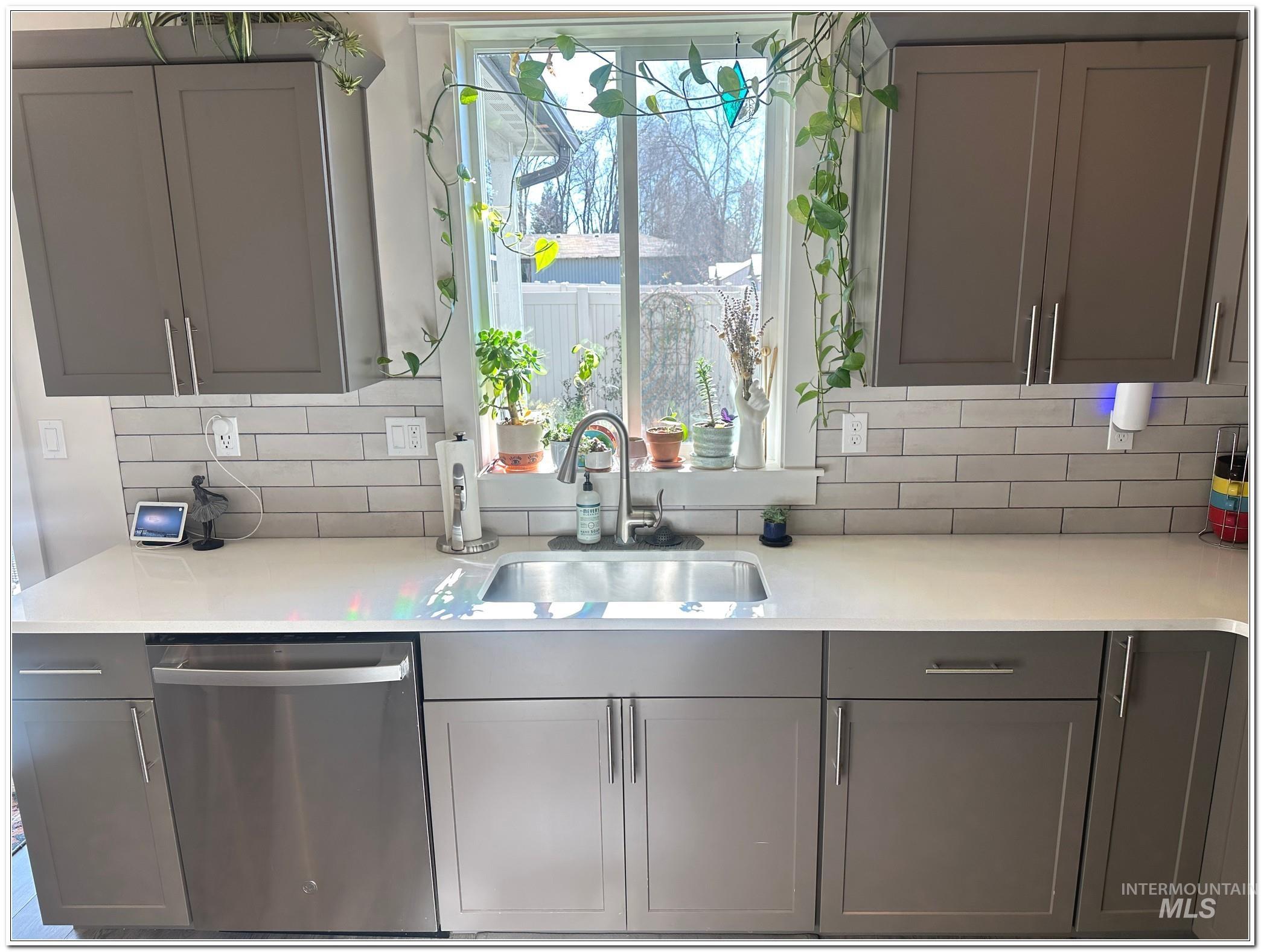 9687 West Arnold Road Boise, ID 83714 - Photo 5 of 49 Kitchen with stainless steel dishwasher, gray cabinets, decorative backsplash, and light stone counters