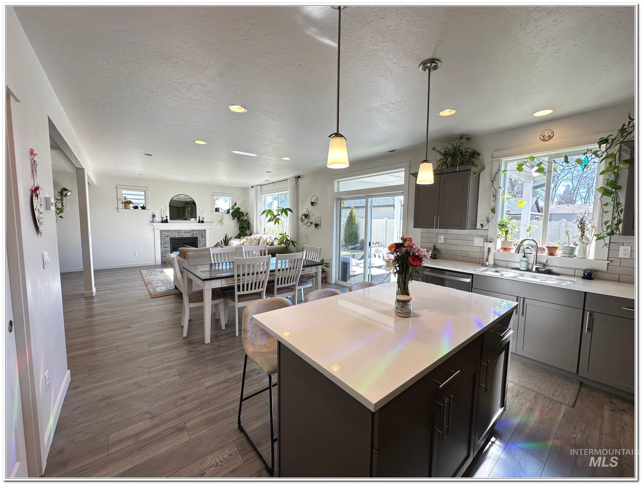 9687 West Arnold Road Boise, ID 83714 - Photo 49 of 49 Kitchen featuring pendant lighting, a fireplace, open floor plan, a center island, and dark wood-style flooring