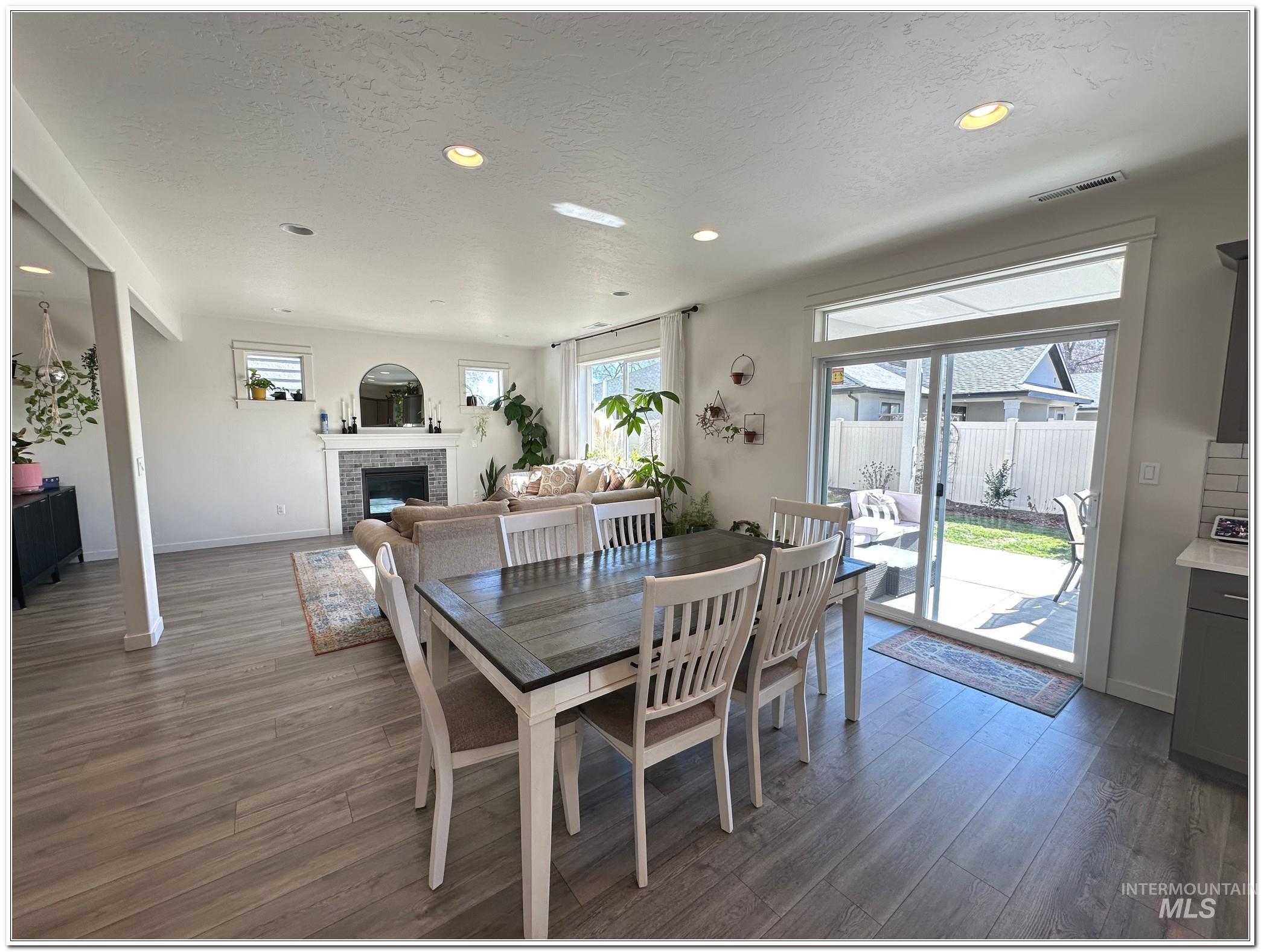 9687 West Arnold Road Boise, ID 83714 - Photo 8 of 49 Dining space featuring dark wood-type flooring, recessed lighting, healthy amount of natural light, a fireplace, and a textured ceiling