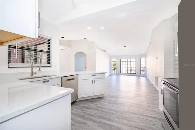 a large white kitchen with a lot of white cabinets and wooden floor